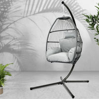 Full view of grey hammock-style hanging egg chair with stand and soft cushion indoors.