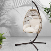 Full view of the rattan hanging egg chair on a lawn, showing its rotation and comfort.