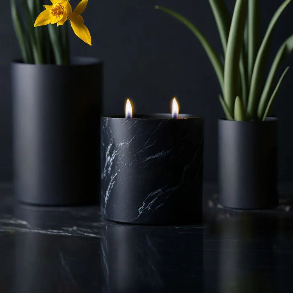 Short matte black ceramic vessel candle photographed under natural light on white background