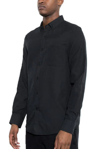Model wearing men's black long sleeve button-down shirt, standing with arms relaxed by sides.