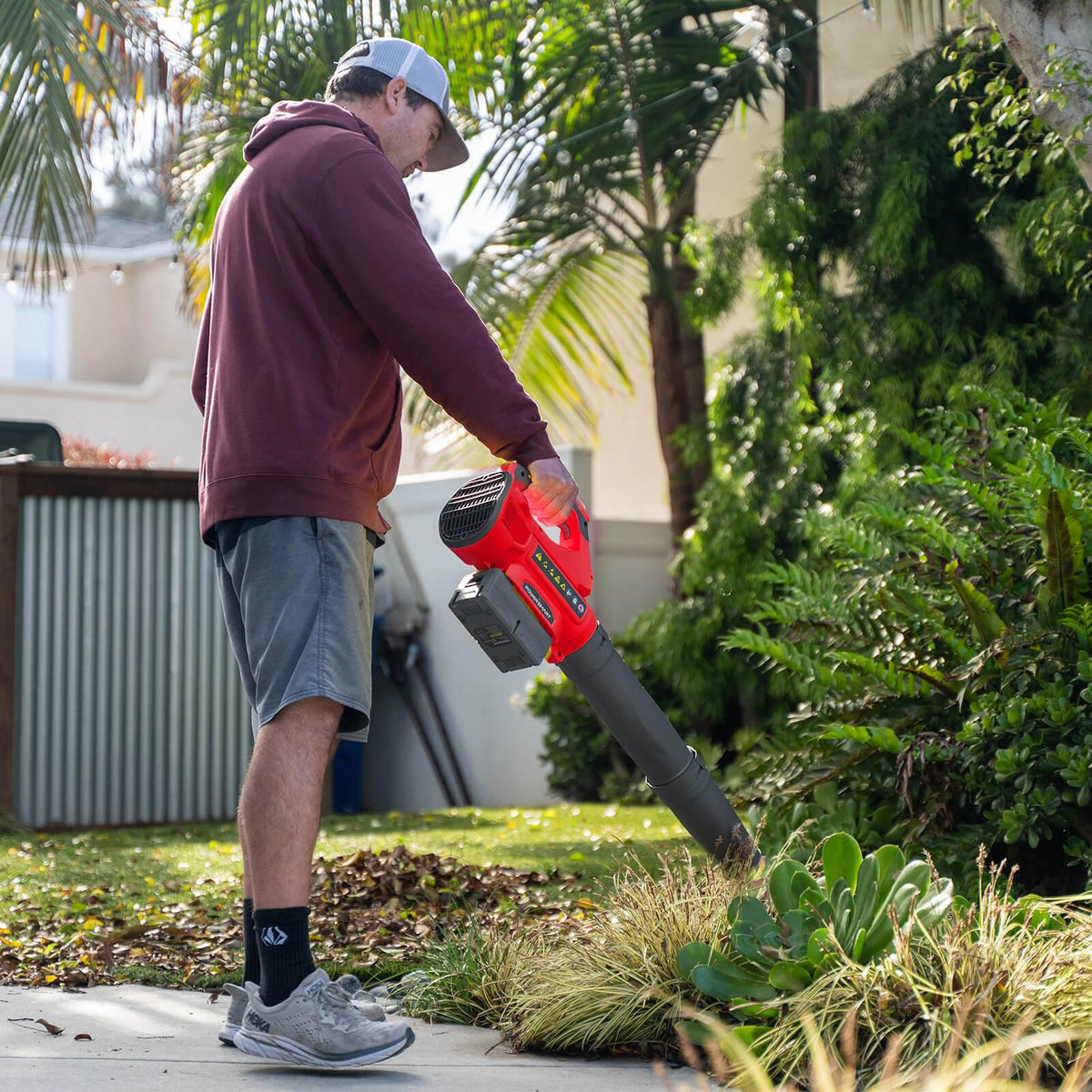 Leaf blower resting on grass with charger and battery ready for outdoor garden work.