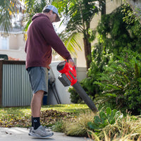 Leaf blower resting on grass with charger and battery ready for outdoor garden work.