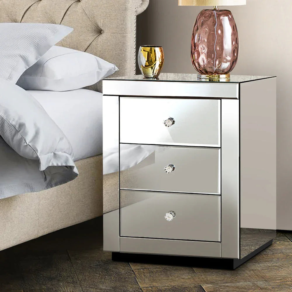 Decorated tabletop of mirrored bedside table with lamp and personal accessories.