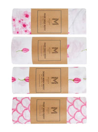 Set of four organic cotton muslin baby swaddles neatly folded with tissue paper and a ribbon.