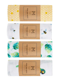 Close-up of four watercolor print organic muslin baby swaddles stacked with bows on a white surface.
