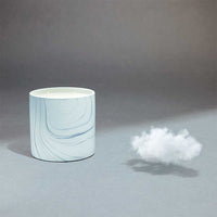 Close-up of hand-painted white marble ceramic candle vessel with swirling gray and black patterns.