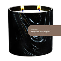 Hand-painted black ceramic candle vessel with white and gold Marquina swirl design, empty.