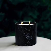 Passionate Fruit Black Marquina Candle placed next to green foliage highlighting marquina design details.