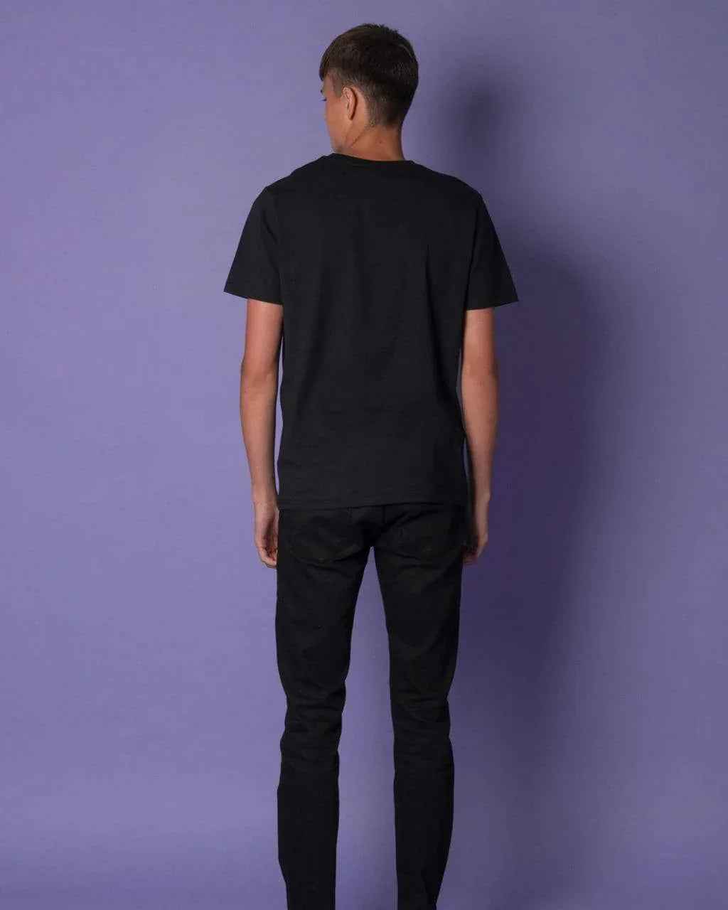 Model wearing black t-shirt showing back view with bee embroidery near neckline.