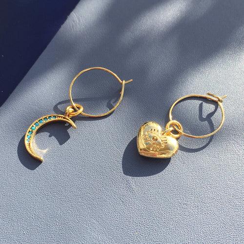 Turquoise crystal moon and chunky heart charm earrings in mini hoop style on light background.