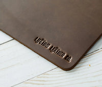 Close-up view of corner of dark brown leather mouse pad showing texture and thickness.