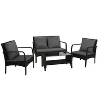 Black wicker outdoor lounge set with two armchairs, two-seater sofa, and glass-top table on wooden deck.
