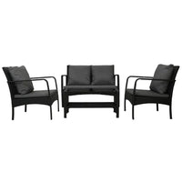 Two armchairs and two-seater loveseat in black rattan wicker with beige cushions arranged outdoors.