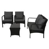 Tempered glass top table with non-slip pads, part of black wicker garden lounge set.