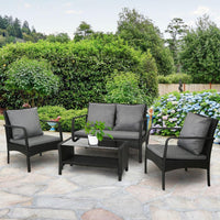 Black woven outdoor furniture set including two armchairs, loveseat, and glass-topped table.