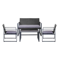 Side view of cushioned black patio chairs around glass-top table on wooden deck.