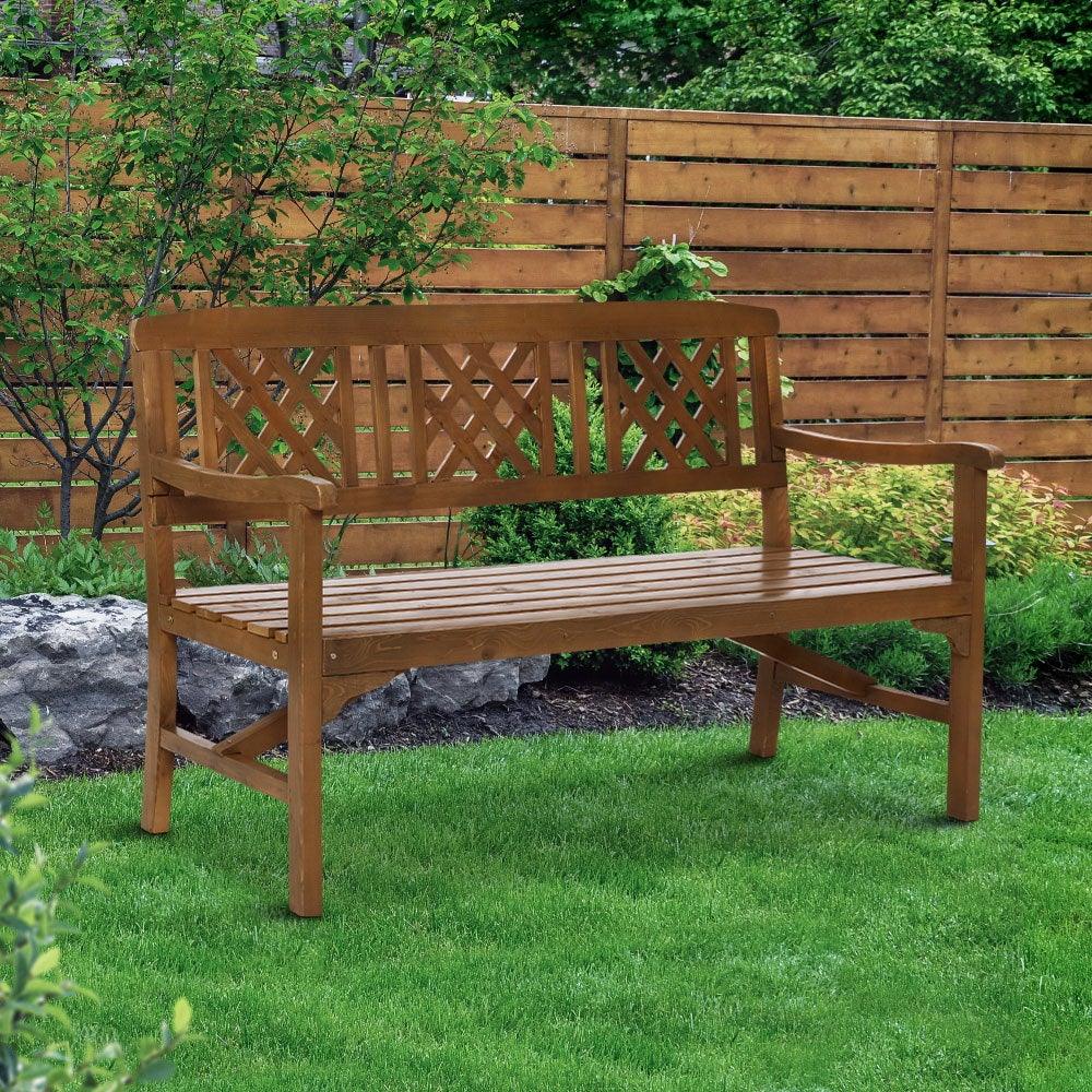 Wooden garden bench with armrests and lattice backrest on outdoor grass background