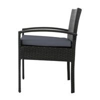 Two black wicker patio chairs arranged beside a wooden deck overlooking yard