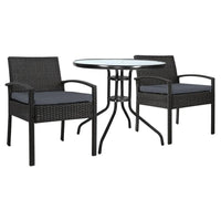 Two wicker garden patio chairs with beige cushions around a glass-top outdoor table.