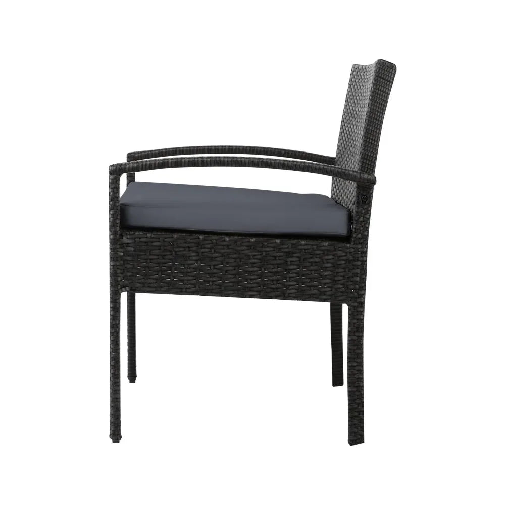 Glass-top outdoor table with wicker chairs arranged for outdoor dining.