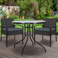 Outdoor patio dining set with two wicker chairs and a round tempered glass-top table.