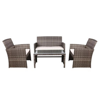 Two-seater rattan outdoor sofa with removable gray cushions placed beside matching armchair on wooden deck.