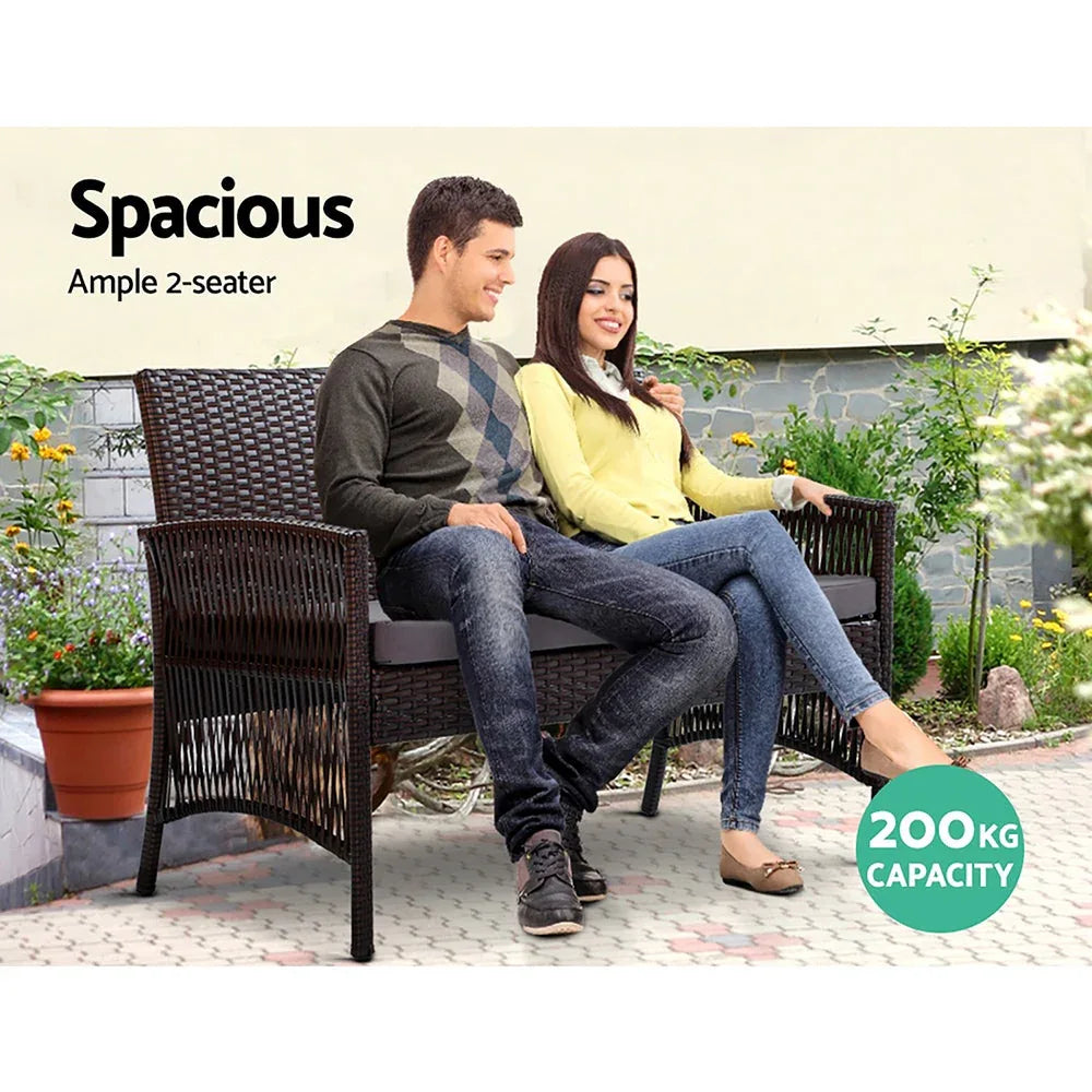 Four-piece black wicker outdoor furniture set arranged neatly on wooden deck.
