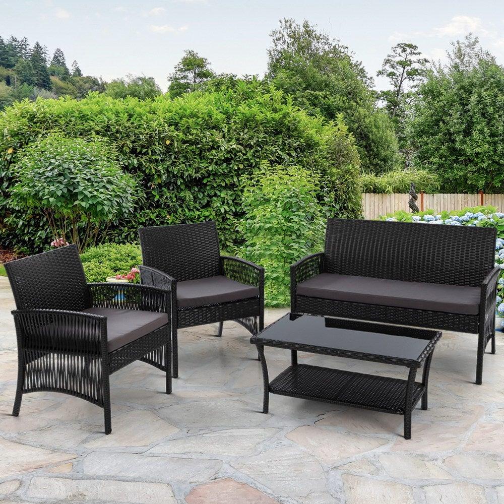 Black wicker armchair with plush cushions set beside small table on outdoor patio.