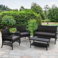 Black wicker armchair with plush cushions set beside small table on outdoor patio.