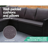 Outdoor furniture set with black wicker sofa pieces and beige cushions on stone patio