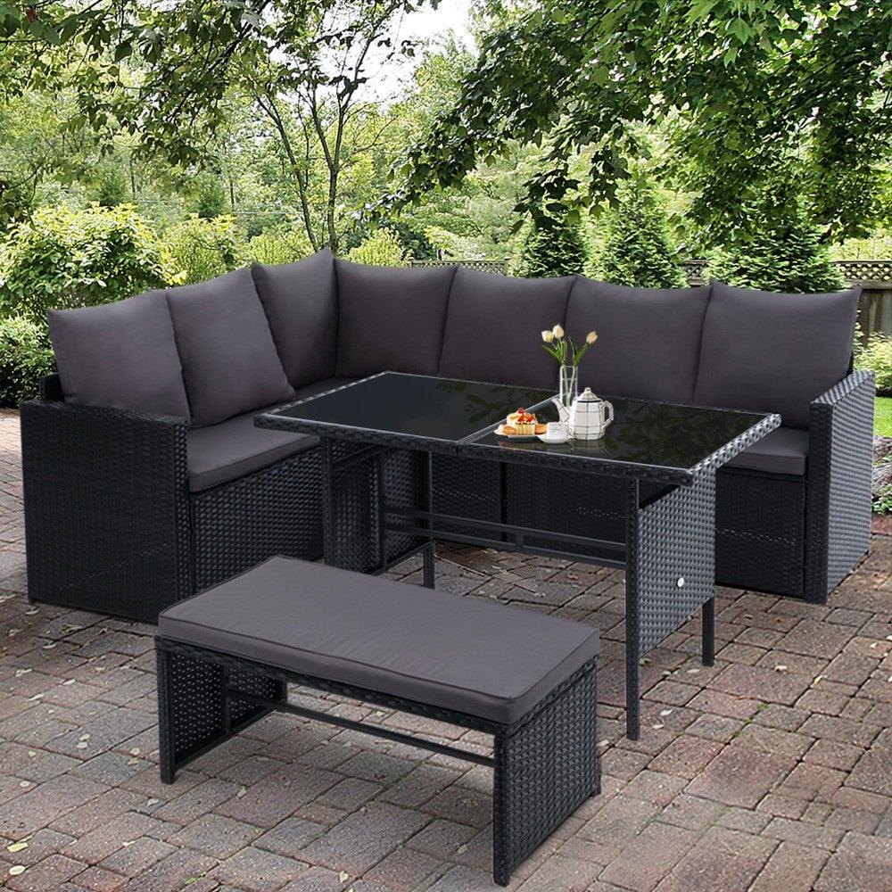 Black wicker corner sofa unit with cushions, part of modular outdoor dining furniture set
