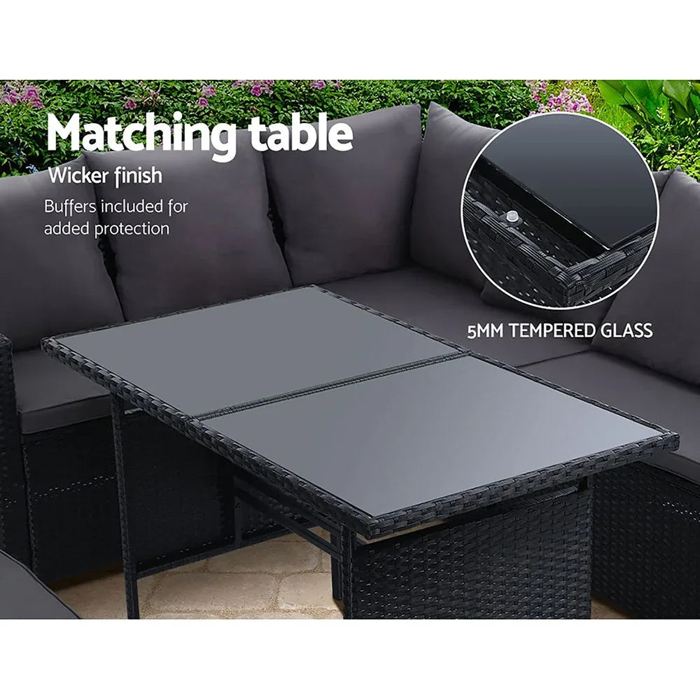 Black wicker outdoor sofa with multiple cream cushions and a small grey pillow on the corner.