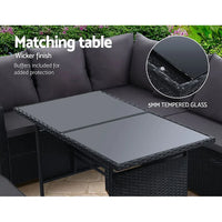 Black wicker outdoor sofa with multiple cream cushions and a small grey pillow on the corner.