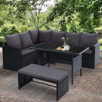 Modular black wicker outdoor seating set configured in an L-shape on a stone floor.
