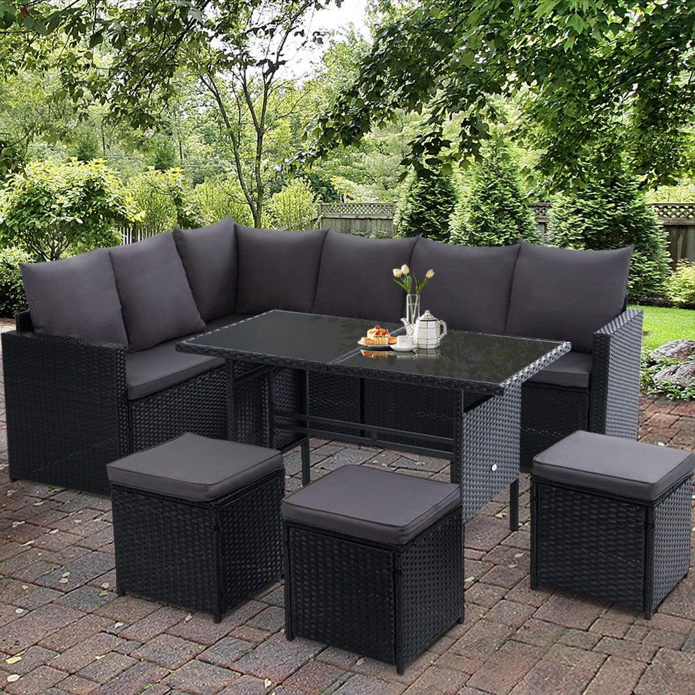 Evening view of outdoor wicker dining sofa set with cushions illuminated by soft ambient lighting.