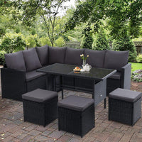 Evening view of outdoor wicker dining sofa set with cushions illuminated by soft ambient lighting.