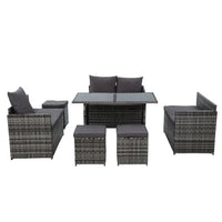 Outdoor dining setup with 9-seater wicker sofa and table on patio with plants.