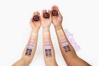 Hand swatching rich purple Sugar Hill Shimmer Powder on skin showing vibrant, creamy shimmer.
