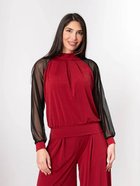Side view of garnet set showing flowy palazzo pants and fitted knit top with delicate sheer sleeves.