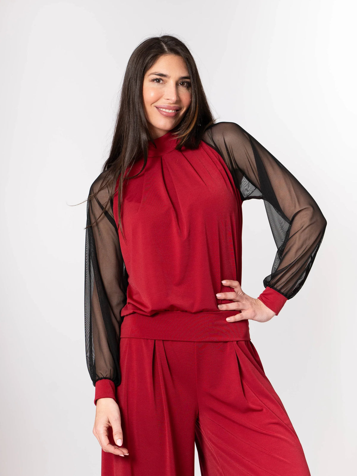 Model posing in garnet palazzo and sheer-sleeved top, highlighting soft fabric texture and elegant fit.