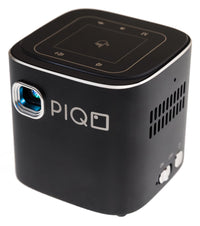 Compact PIQO mini projector projecting a bright image on a wall in a dim room.