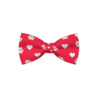 Red dog bow tie patterned with hearts and paw prints, shown flat.