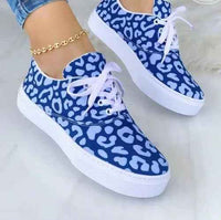 Women's white sneakers with colorful graffiti-style designs on the sides, shown against a neutral background.