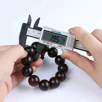 Mini vernier caliper positioned next to ruler displaying measurement readiness.
