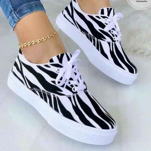 White women's sneakers with colorful graffiti-style designs, thick soles, and lace-up fronts on a plain background.