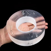 A roll of transparent, double-sided adhesive tape displayed on a clean, white surface.