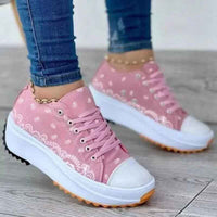 White canvas sneakers with a colorful pattern, lace-up design, and a thick rubber sole, shown on a plain background.