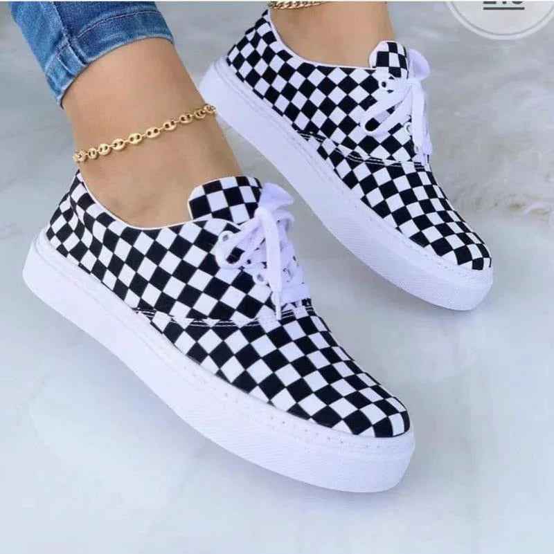 White women’s sneakers with colorful graffiti designs and chunky soles, displayed against a plain background.