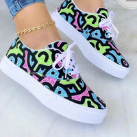 White women's sneakers with colorful graffiti designs, chunky sole, and lace-up closure displayed on a plain background.