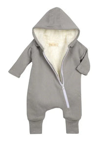 Baby smiling wearing gray jumpsuit with bib attached, sitting and playing.